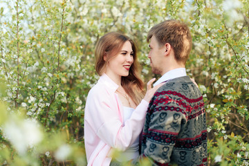 a young couple in love cuddles against the background of blooming spring cherry orchards 1