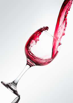 Wave formed on the pouring of red wine on a glass against a white background