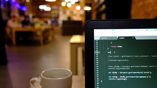 HTML, CSS and JavaScript code developing. Website design code programming on a laptop screen. Table with laptop and coffee cup