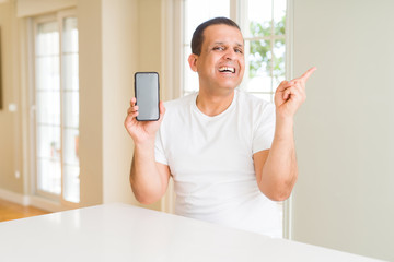 Middle age man showing smartphone screen very happy pointing with hand and finger to the side