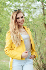 Obraz premium beautiful blonde girl in a yellow jacket on the background of nature outdoors 1