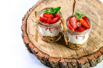 Summer dessert, classic cheesecake with strawberries decorated with mint leaves on a wooden stump. Copy space