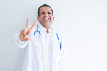 Fototapeta premium Middle age doctor man wearing stethoscope and medical coat over white background smiling looking to the camera showing fingers doing victory sign. Number two.
