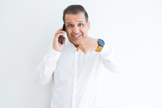Middle age man calling using smartphone with surprise face pointing finger to himself
