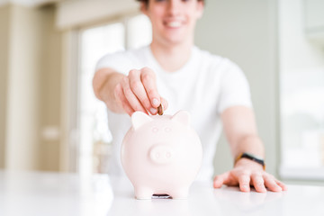 Close up of man putting a coin inside piggy bank as saving or investment