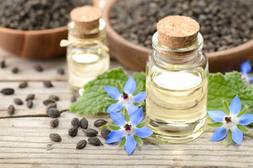Fototapeta na wymiar borage oil in the glass bottle, with seeds and flowers