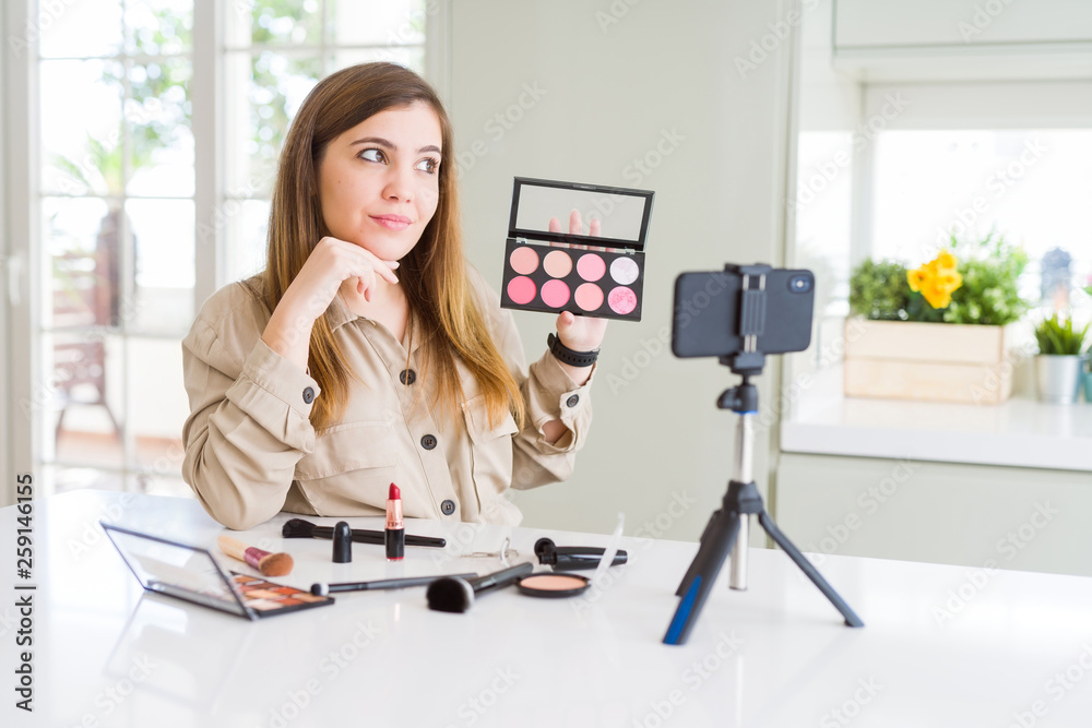 Sticker Beautiful young influencer woman recording make up video tutorial serious face thinking about question, very confused idea