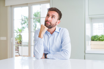 Handsome business man with hand on chin thinking about question, pensive expression. Smiling with thoughtful face. Doubt concept.