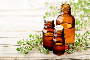 thyme essential oil and thyme flowers on the wooden board