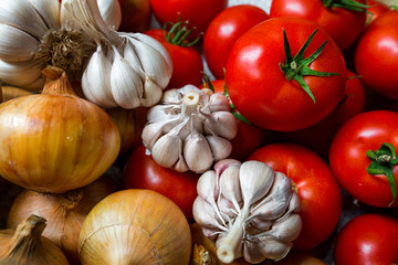 Ripe, fresh, harvested vegetables on table. Onions, tomatoes, garlic on kitchen table prepared to make a delicious vegetarian meal or for canning veggies for winter in jars. Concept of healthy eating