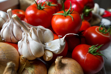 Ripe, fresh, harvested vegetables on table. Onions, tomatoes, garlic on kitchen table prepared to make a delicious vegetarian meal or for canning veggies for winter in jars. Concept of healthy eating
