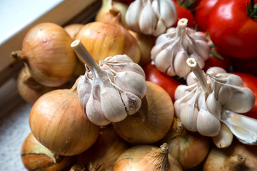 Ripe, fresh, harvested vegetables on table. Onions, tomatoes, garlic on kitchen table prepared to make a delicious vegetarian meal or for canning veggies for winter in jars. Concept of healthy eating