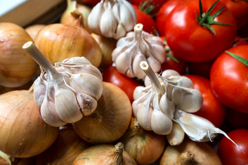 Ripe, fresh, harvested vegetables on table. Onions, tomatoes, garlic on kitchen table prepared to make a delicious vegetarian meal or for canning veggies for winter in jars. Concept of healthy eating