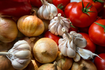 Ripe, fresh, harvested vegetables on table. Onions, tomatoes, garlic on kitchen table prepared to make a delicious vegetarian meal or for canning veggies for winter in jars. Concept of healthy eating