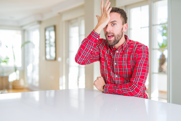 Handsome man wearing colorful shirt surprised with hand on head for mistake, remember error....