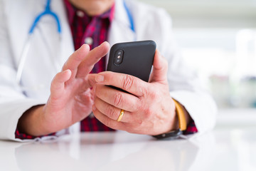 Close up of doctor man hands using smartphone and wearing stethoscope