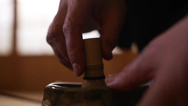 Japanese tea ceremony. Master mixes tea with hot water using a tea whisk (chasen)