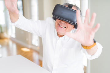 Naklejka na ściany i meble Man wearing virtual reality glasses smiling looking very happy and excited