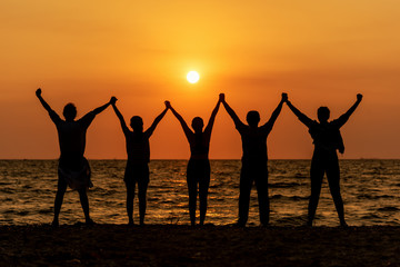 Fototapeta na wymiar Silhouette of friends and teamwork standing on beach during sunset time for success business. Lifestyle and Teamwork Concept