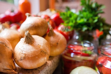 Canning fresh tomatoes with onions in jelly marinade. Woman hands putting red ripe tomato slices and onion rings in jars. Basil, parsley leaves on top of onions. Vegetable salads for winter