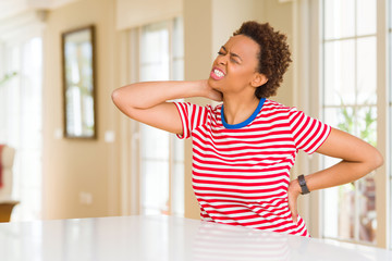 Young beautiful african american woman at home Suffering of neck ache injury, touching neck with hand, muscular pain