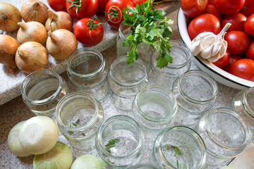 Canning fresh tomatoes with onions in jelly marinade. Woman hands putting red ripe tomato slices and onion rings in jars. Basil, parsley leaves on top of onions. Vegetable salads for winter