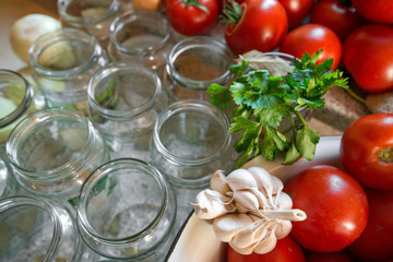 Canning fresh tomatoes with onions in jelly marinade. Woman hands putting red ripe tomato slices and onion rings in jars. Basil, parsley leaves on top of onions. Vegetable salads for winter