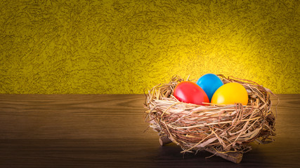 Ein Osternest mit bunte Ostereier auf einem Holz Tisch