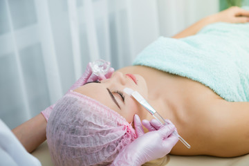 spa, cosmetologist applying cream mask on face