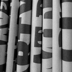Black and white image of newspapers folded flat and in a vertical position