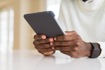 Close up of african business man using touchpad tablet, working sitting on a desk