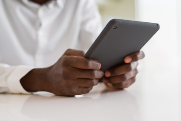 Close up of african business man using touchpad tablet, working sitting on a desk