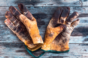 Old and dirty working gloves over wooden table,  gloves for each finger.