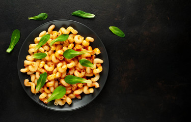 Delicious Italian pasta with tomato sauce, on a plate on a dark table. View from above