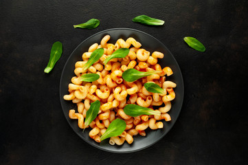 Delicious Italian pasta with tomato sauce, on a plate on a dark table. View from above