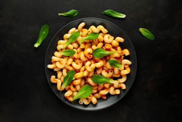 Delicious Italian pasta with tomato sauce, on a plate on a dark table. View from above