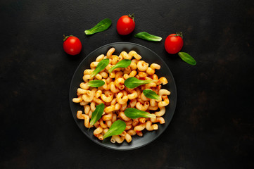 Delicious Italian pasta with tomato sauce, on a plate on a dark table. View from above