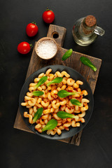 Delicious Italian pasta with tomato sauce, on a plate on a dark table. View from above