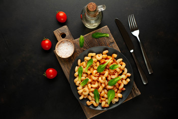 Delicious Italian pasta with tomato sauce, on a plate on a dark table. View from above