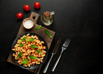 Delicious Italian pasta with tomato sauce, on a plate on a dark table. View from above