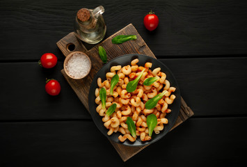 Delicious Italian pasta with tomato sauce, on a plate on a dark wooden table. View from above