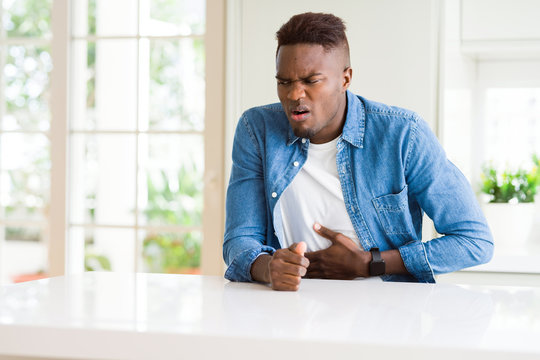 Handsome african american man at home with hand on stomach because indigestion, painful illness feeling unwell. Ache concept.