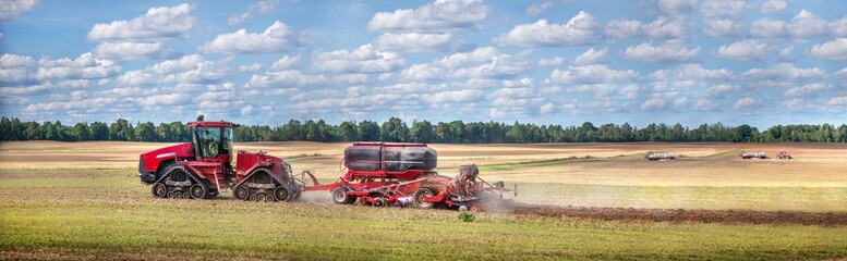 Agricultural background with red tractor pulling plow, throwing dust in air. Combine harvester at wheat field. Heavy machinery during cultivation, working on fields. Dramatic sky, rain, storm clouds
