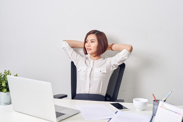 Business woman resting in the office after a working day leaning back her hands behind her head