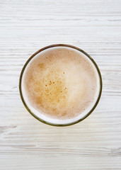 Glass of light beer over white wooden surface, top view. Overhead.