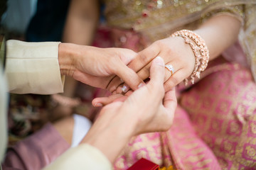 groom wears ring on bride's finger in wedding Thailand ceremony