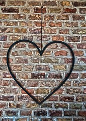 Rusty iron heart hanging on a brick wall