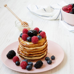 Homemade pancakes with berries and honey, side view. Closeup.