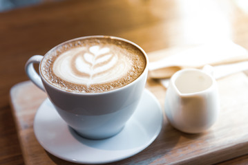 Coffee Espresso. Cup Of Coffee with latte art foam on wood table near window with light shade.