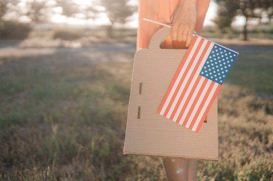 Memorial day sale, Independence day sale. Female hand with paper bag and american flag in spring or summer park